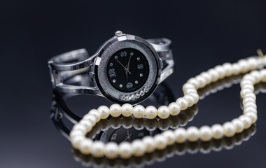 Women's watch in the original metal case and a pearl necklace