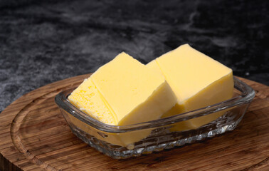 Sliced blocks of butter in glass dish on cutting board