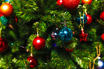 Christmas decorations hang on the tree with multi-colored glass balls