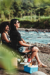 Vertical de una Mujer y un hombre sentados disfrutando de un día soleado a la orilla de un río