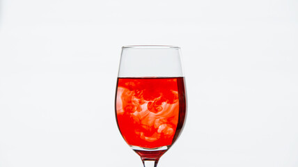Red ink drips into the glass with water and creates beautiful colored lines.
