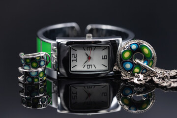 Unusual women's watch with a metal strap with green inserts and silver jewelry with a blue-green color