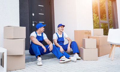 Two removal company workers have a break while sitting on the step
