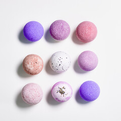 Flat lay composition with bath bombs pink, violet, purple colored on white paper background. Bathing balls with  essential oils for relaxation and aromatherapy. Body care natural products