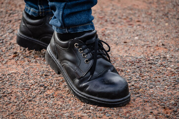 Man wearing safety shoes black color, standing on the ground