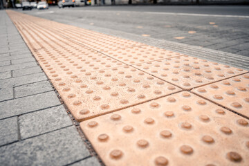 Yellow Braille blocks on public transport station for person with a physical disability
