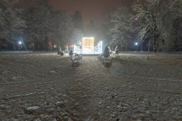 Świąteczna iluminacja w parku dworskim w mieście Iłowa w Polsce. Jest zimowa noc, widok jest...