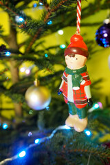Obraz premium a wooden toy boy is hanging on a Christmas tree with glowing garlands. side view