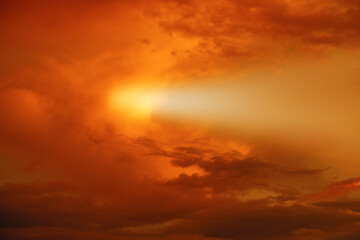 Fototapeta na wymiar The sun behind the clouds at sunset. Evening sky.