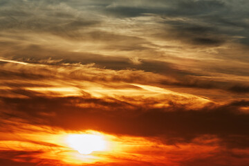Naklejka na ściany i meble The sun behind the clouds at sunset. Evening sky.