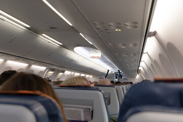 The cabin of the plane with passengers in their seats before takeoff. Public place. Selective focus. Close-up