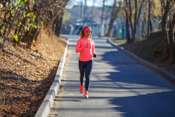 Young fitness girl jogging on the road in the frosty morning.