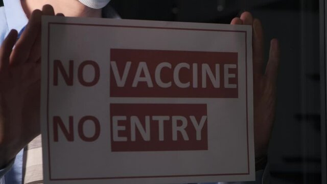 Only for vaccinated. Mans hands attaching sign on the glass in pandemic time., close-up. Pandemic of coronavirus. Descrimination. Vax. Vaccination. Covid-19