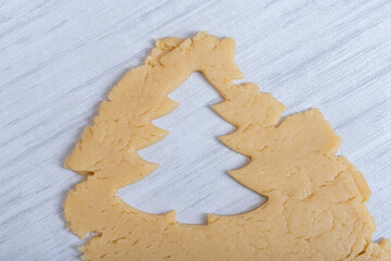 Christmas and New Years tradition. Family home bakery. Cooking traditional gingerbread cookies. The shape of a Christmas tree cut from raw dough. Christmas cookies