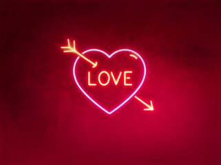 Neon luminous board of a heart with an arrow through it and the word love on red wall background. valentines day concept.