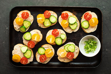 Tapas appetizer canapes with cheese and vegetables and microgreens. Top view .