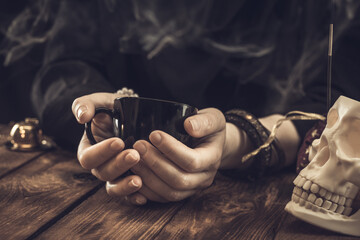 Fortune teller or oracle with holding a black cup for fortune telling on the coffee grounds....