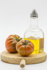 two tomatoes and an oil can on a wooden board