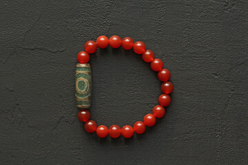 Carnelian stone Dzi bead 3 eyes bracelet. Bracelet made of stones on hand from natural Carnelian. Handmade jewelry bracelets on light background. Tibetan dzi beads 3. Buddhism, fulfillment of desires