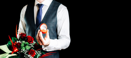 Marry me. Young happy man holding red gift box with diamond engagement ring, red roses bouquet. Engagement marriage ring.