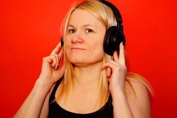Fototapeta premium A woman listens to music with headphones, enjoying the melody. Portrait of a beautiful woman in close-up without makeup.