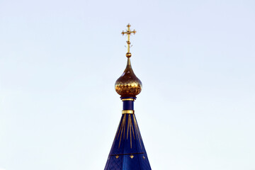 Golden church dome with a cross on the sky background
