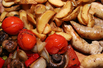Baked potatoes with meat, mushrooms, grilled sausages on a board close-up