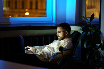 Overworked programmer freelancer in dark night coworking space work on laptop. Workaholic...