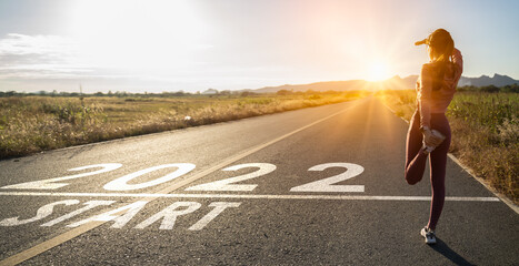 New year 2022 or start straight concept.word 2022 written on the asphalt road and athlete woman...