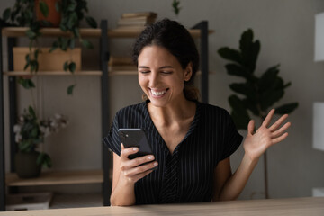 Excited young Latin woman feel euphoric win online lottery on smartphone. Smiling Hispanic female...