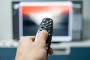  hand with TV remote control on the background with tv