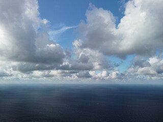 Abstract airy sky with moving plump clouds over the sea ocean. Small waves on clear water surface bokeh lights from sunrise. Holiday, vacation and recreational concept