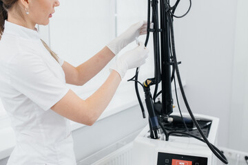 A cosmetologist sets up a modern device with a laser in a beauty salon. Laser pulses cleanse the skin. Hardware cosmetology. The process of photothermolysis, warming the skin. 