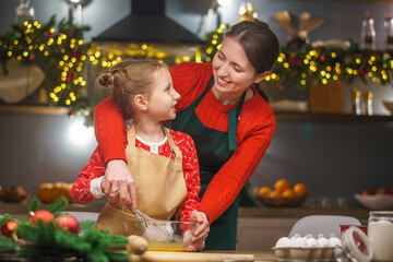 Merry Christmas. My daughter helps my mother cook. Family cooking of festive food. Mother and daughter are making Christmas cookies. happy holidays. Evening time, happy family in the kitchen.