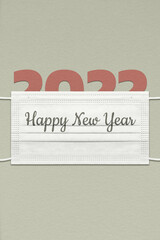 The greeting card with the number 2022 under a face mask with the inscription Happy New Year.