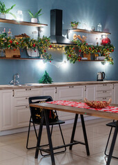 Christmas home room with Christmas tree and festive bokeh lighting, on background kitchen decorated for holiday . Christmas and new year interior-blurred background. Lots of lights that glow in dark.