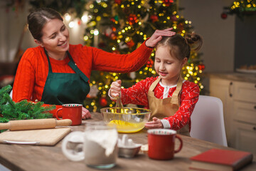 Merry Christmas. My daughter helps my mother cook. Family cooking of festive food. Mother and daughter are making Christmas cookies. happy holidays. Evening time, happy family in the kitchen.