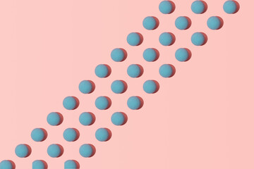 Creative 3D pattern, pastel blue balls in diagonal lines against pink background.  Summer time, beach umbrellas, aerial view.