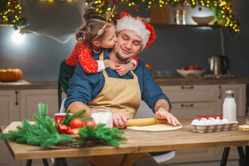 Merry Christmas. My daughter helps my dad cook. Family cooking of festive food. father and daughter are making Christmas cookies. happy holidays. Evening time, happy family in the kitchen.