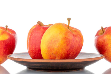Four juicy red apples on a clay dish, close-up, isolated on white.