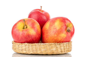 Three juicy red apples with a straw plate, close-up, isolated on white.