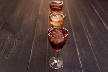 Alcoholic drinks in glass piles on a wooden table. Cherry, nut and lemon liqueurs.