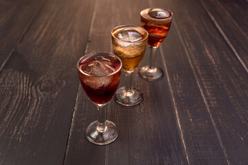Alcoholic drinks in glass piles on a wooden table. Cherry, nut and lemon liqueurs.
