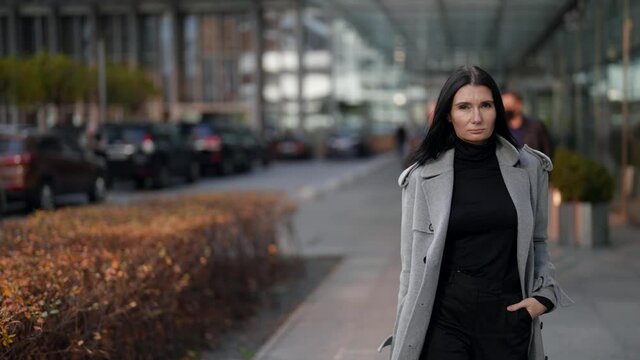 confident and serious woman is walking in business district in downtown, wealthy and rich lady
