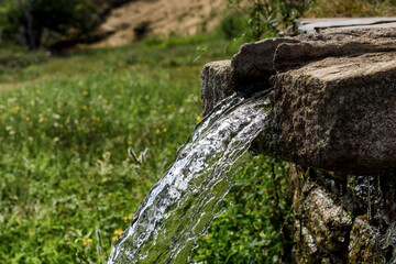 Cascada de agua zen cayendo de una fuente artesanal fabricada en granito.