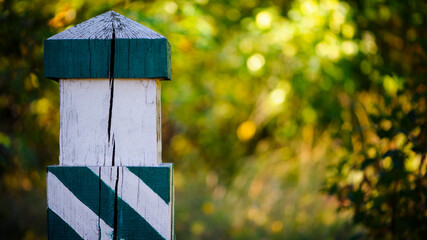 Quarterly pillar in the forest. A wooden pillar for a landmark in the forest. Forestry post. wood post with green stripes, natural background. space for text. autumn leaves in the forest