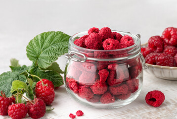 freeze-dried raspberries in a glass jar, fresh raspberries with leaves