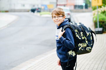 Happy little kid boy with satchel and eyeglasses. Schoolkid wearing glasses on the way to middle or...