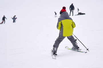 Fototapeta na wymiar A teenage boy carefully skis down a snow-covered mountainside. He is a novice skier. Copy space.