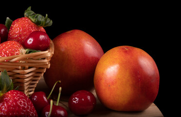 Bamboo board with tasty strawberries, delicious cherries and succulent nectarines.